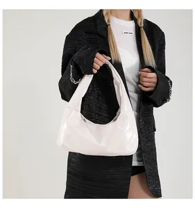 Chic cream patent leather hobo bag with sleek finish and minimalist shoulder strap design