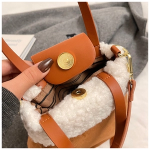 Detail view of the brown suede crossbody bag with plush white trim and striped lining