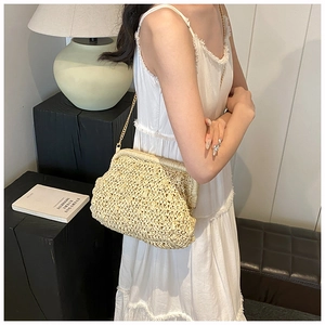 Macro detail of beige handwoven straw clutch featuring textured weave and gold chain