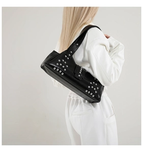 Détail du sac bandoulière en similicuir noir avec clous argentés et boucles punk