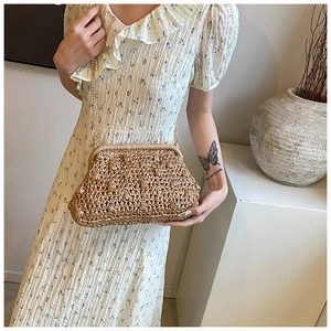Detail of straw woven clutch bag with gold chain strap and vintage clasp closure