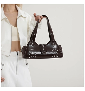 Détail du sac à main en cuir verni marron foncé avec clous argentés et texture style punk