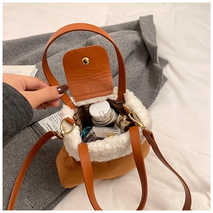 Detail of brown suede bucket bag with white fleece trim and makeup items inside