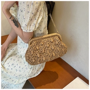 Detail of straw woven clutch bag with popcorn stitch texture and gold chain strap