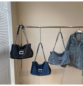Detailed view of denim tote bags in black and blue with metal chain straps and silver buckles