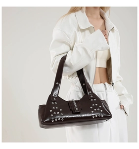 Détail d'un sac porté épaule punk marron foncé avec rivets argentés sur cuir lisse