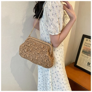 Detail of straw woven cloud bag with gold chain strap on model in minimalist interior