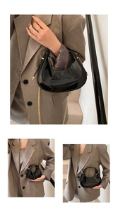 Détail du sac croissant en cuir verni noir avec chaîne dorée et fini brillant