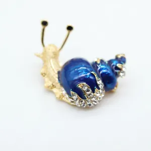 Macro shot of gold-plated snail brooch with blue enamel and sparkling rhinestones