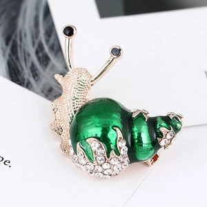 Macro shot of snail brooch with green enamel shell and sparkling crystal rhinestones
