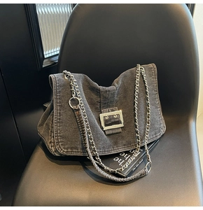Detailed macro view of retro grey washed denim shoulder bag with bold silver metal buckle