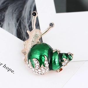 Macro detail of a green enamel snail brooch with sparkling white rhinestones on gold alloy