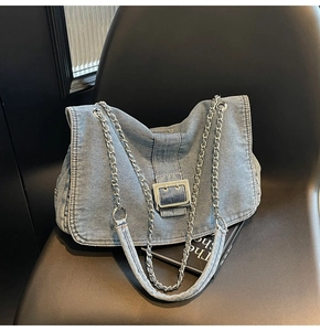 Detail of light blue denim bag with silver chain strap and large metal buckle