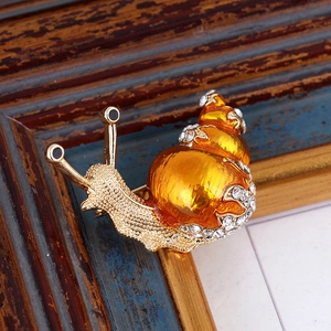 Enamel snail brooch with gold base, orange shell and sparkling white rhinestones
