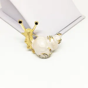 Macro detail of snail brooch featuring gold alloy base with white enamel and rhinestones