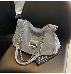 Detailed view of light blue denim shoulder bag with silver chain and metal buckle