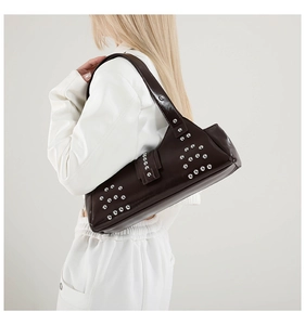 Détail du cuir brillant marron foncé avec rivets argentés sur un sac moto vintage