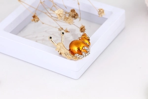 Macro shot of snail brooch featuring amber enamel shell and white rhinestones