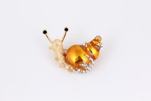 Macro detail of snail brooch with orange enamel shell and sparkling white rhinestones