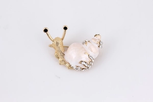 Macro detail of enamel snail brooch with sparkling rhinestones and golden alloy finish