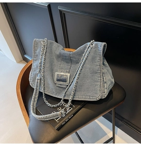 Detailed view of blue denim shoulder bag with silver buckle and chain strap