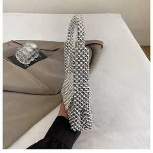 Close-up of a silver beaded woven evening handbag with reflective faceted texture