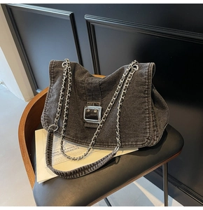 Detail of vintage denim shoulder bag with metal buckle and chain strap on chair