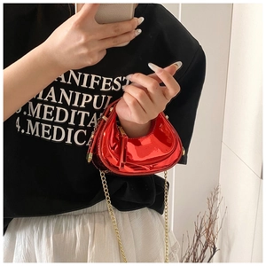 Détail du mini sac demi-lune en cuir verni rouge avec bandoulière chaîne dorée