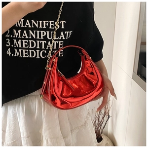 Détail du sac croissant en cuir verni rouge avec chaîne dorée sur la tenue du mannequin