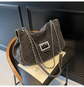 Detail of grey washed denim tote featuring a large silver metal buckle and chain strap