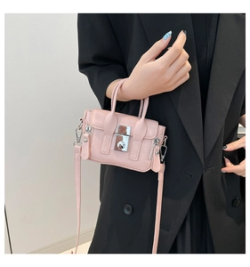 Gros plan du mini sac carré rose clair avec fermoir rotatif argenté et texture en cuir PU