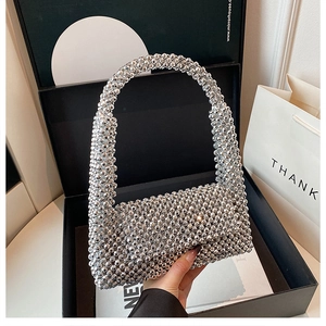 Detailed view of silver beaded evening bag with shimmering metallic pearls in a gift box