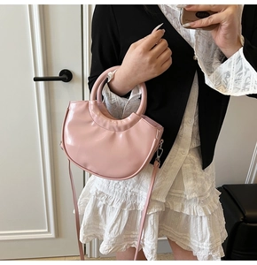 Detail of pink semi-circular leather handbag with smooth glossy finish and round handle