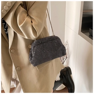 Close-up of black rhinestone evening clutch bag with elegant gold chain shoulder strap