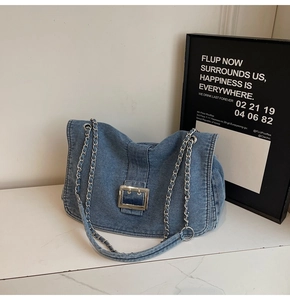 Detail of blue denim tote bag with silver chain strap and metal square buckle