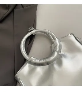 Détail du sac à main argenté métallisé avec poignées rondes et texture cuir lisse