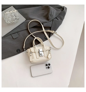 Gros plan d'un mini sac bandoulière crème à côté d'un smartphone montrant sa taille compacte