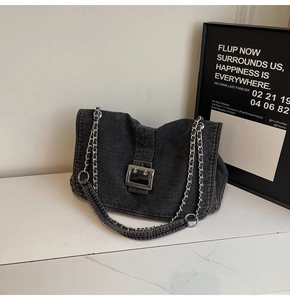 Macro view of washed dark denim texture with large silver metal buckle on a shoulder bag