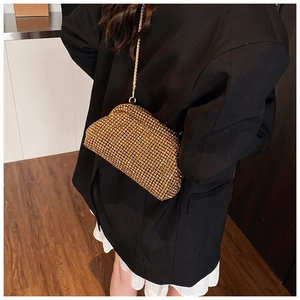 Close-up of elegant gold rhinestone evening bag with chain strap worn as a crossbody bag
