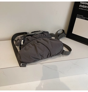 Detailopname van de donkergrijze geplooide nylon rugzak op wit marmer display
