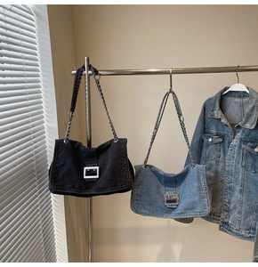 Detail of denim tote bags with square metal buckles and chain straps in black and light blue