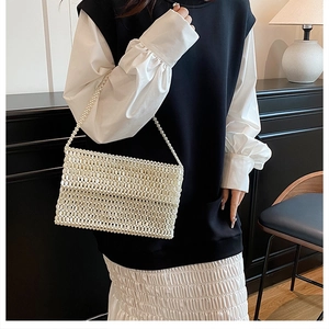 Detail of white handmade pearl beaded bag with elegant chain strap shown on a model