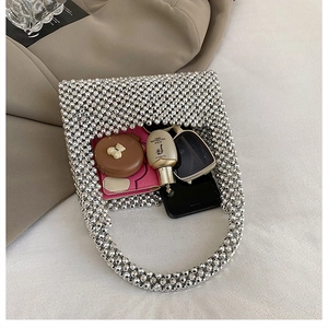 Flat lay showing silver beaded handbag capacity with wallet, cosmetics and sunglasses