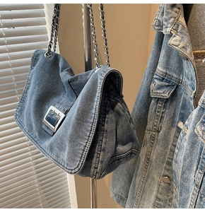Detail of blue wash denim handbag showing heavy texture and silver metal buckle accent