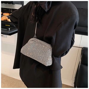 Close-up of a silver rhinestone dumpling bag with metal chain on a black suit
