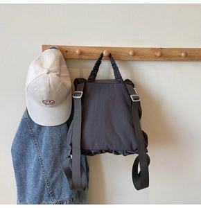 Detail view of the gray nylon backpack with pleated bottom and adjustable webbing straps