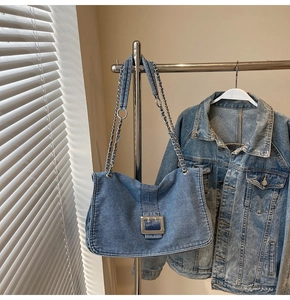 Close-up of vintage washed denim shoulder bag with silver buckle and chain strap detail