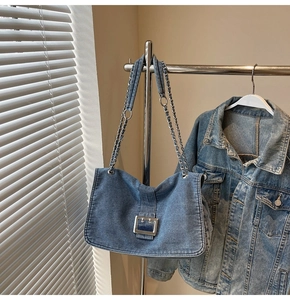 Detail of blue denim tote bag featuring large silver metal buckle and chain strap