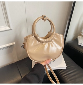 Detail of moon-shaped handbag with round handle and smooth faux leather texture