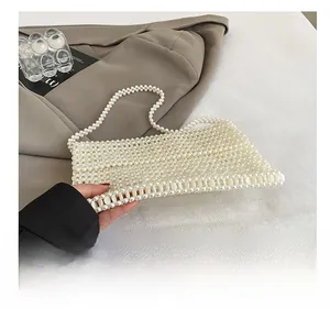 Detail showing handcrafted pearl beaded strap and top handle design of the cream tote bag